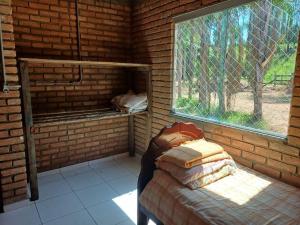 um quarto com uma cama e uma janela numa parede de tijolos em Casa de Campo Trevão - Queluzito em Conselheiro Lafaiete