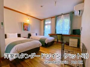 a hotel room with two beds and a television at Lodge Atelier in Hokuto