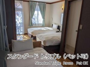 a hotel room with two beds and a window at Lodge Atelier in Hokuto