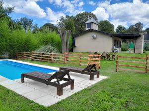 een achtertuin met een zwembad en twee banken naast een hek bij Chalet El Buho in Villa General Belgrano