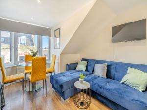 a living room with a blue couch and a table at Apartment Six - Uk44288 in Arbroath