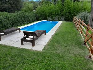 una piscina con 2 bancos y una mesa de picnic en Chalet El Buho en Villa General Belgrano