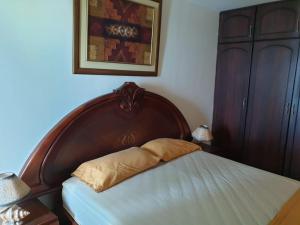 - un lit avec une tête de lit en bois dans une chambre dans l'établissement Departamento al pie del mar Torre Marina, à Salinas
