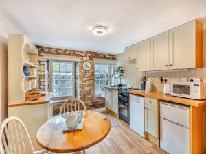 a kitchen with white cabinets and a wooden table at Cauldron Falls in West Burton