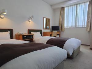 um quarto de hotel com duas camas e uma televisão em New Grand Hotel em Shinjo