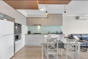 una cucina con armadi bianchi, tavolo e sedie di Light apartment in amazing central location a Brisbane