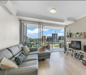 a living room with a couch and a large window at Light apartment in amazing central location in Brisbane