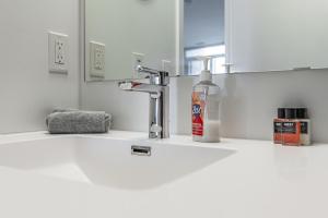 un lavandino in bagno con una bottiglia di sapone e uno specchio di Luxury properties close to Eaton Center! a Toronto