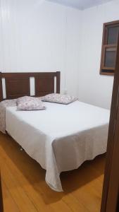 een slaapkamer met een bed met witte lakens en een houten vloer bij Casa da Mari in Canela