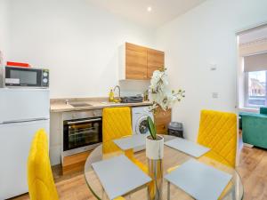 a kitchen with a dining table and yellow chairs at Apartment Three - Uk44286 in Arbroath