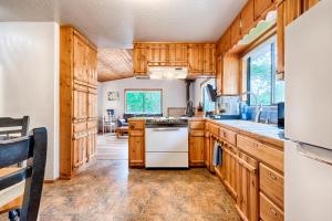 a kitchen with wooden cabinets and a white dishwasher at Petite Chalet with deck near Loch Lomond! in Kelseyville