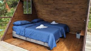 2 camas individuales en un dormitorio con paredes de madera en Mamaterra Glamping, en Macanal