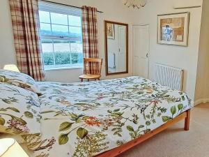 a bedroom with a bed with a floral bedspread and a window at Foston Grange Cottage in Bulmer