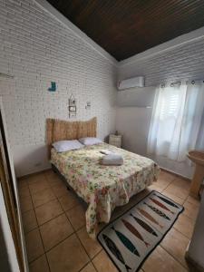 um quarto com uma cama com colcha floral em Guaiuba's House no Guarujá