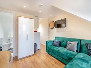 a living room with a green couch and a kitchen at Apartment Five - Uk44289 in Arbroath