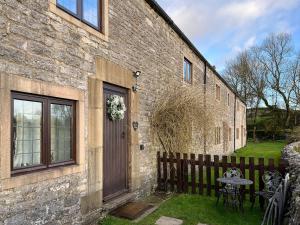 a brick house with a wooden door and a table at Denver Cottage - Uk46029 in Monyash