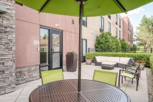 a table with a green umbrella on a patio at SpringHill Suites Terre Haute in Terre Haute