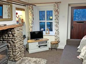 a living room with a tv and a fireplace at Bluebell Cottage in Garstang