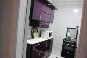 una pequeña cocina con armarios morados y microondas en Entire rental unit in New Cairo, Egypt en El Cairo
