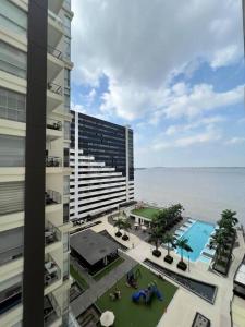 a view of a building with a pool and the ocean at Depa en piso alto! Vista al rio y parqueo in Guayaquil