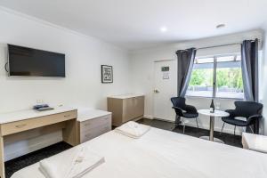 a bedroom with a bed and a desk and two chairs at Manjimup Kingsley Motel in Manjimup