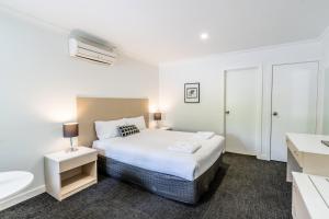 a white bedroom with a bed and a sink at Manjimup Kingsley Motel in Manjimup