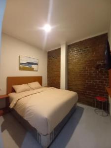 Cama grande en habitación con pared de ladrillo en Pondok Indah24 Hotel en Yakarta