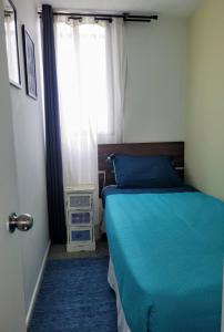 Un dormitorio con una cama azul y una ventana en Cómodo departamento a una cuadra de Playa la Herradura, en Coquimbo