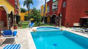 a swimming pool in a yard next to a building at Casa Colonial, Cozumel in Cozumel