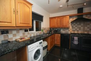 a kitchen with wooden cabinets and a washing machine at Free Parking - Large House - Groups - Contractors - Loughborough in Loughborough +30 photos