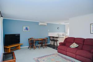een woonkamer met een rode bank en een tafel bij Near Murray River - A Lovely Holiday Unit in Moama in Moama