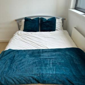 a bed with a blue blanket and two blue pillows at SECC Ovo Apartments in Glasgow