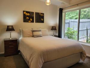 a bedroom with a bed with two lamps and a window at Healesville Schofield Cottage in Healesville