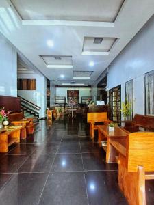 un restaurante con mesas de madera y bancos en una habitación en San Juanico Travellers Inn - RedDoorz en Tacloban