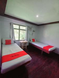 um quarto com duas camas e uma janela em San Juanico Travellers Inn - RedDoorz em Tacloban