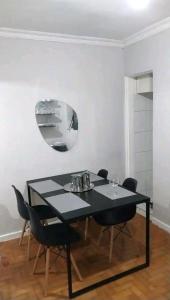 a dining room table with black chairs and a mirror at Magnífico apartamento in Rio de Janeiro