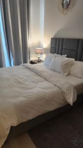 une chambre avec un grand lit blanc avec une lampe dans l'établissement Ensuite one bedroom in a 2-bedroom with a shared living room, à Dubaï