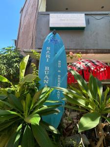 a blue surfboard sitting in the middle of plants at Sari Buana Bed & Breakfast in Kuta