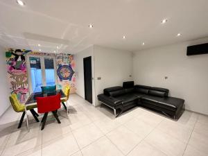 una sala de estar con un sofá de cuero negro y sillas en Le Victor Hugo - SPA, en Nevers
