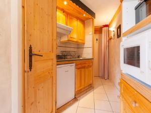 una cocina con armarios de madera y un aparato blanco en Studio Avoriaz, 1 pièce, 3 personnes - FR-1-314-237, en Morzine