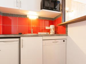 uma cozinha com armários brancos e paredes vermelhas em Appartement Avoriaz, 2 pièces, 5 personnes - FR-1-314-257 em Morzine
