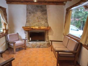a living room with two chairs and a stone fireplace at Cabaña El Viaje in San Carlos de Bariloche