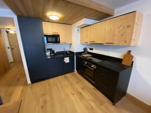 a kitchen with a black counter and wooden cabinets at Spacieux et Moderne Appartement de 67m² à La Chapelle-d'Abondance, Balcon Exposé Ouest - FR-1-692-94 in La Chapelle-dʼAbondance +6 photos