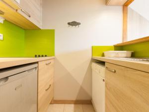a kitchen with green and white walls and wooden cabinets at Appartement Avoriaz, 2 pièces, 5 personnes - FR-1-314-264 in Morzine