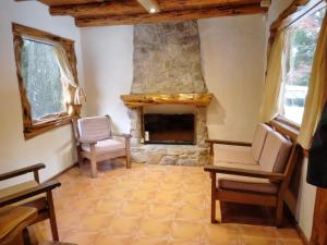 ein Wohnzimmer mit einem Steinkamin und Stühlen in der Unterkunft Cabaña El Viaje in San Carlos de Bariloche