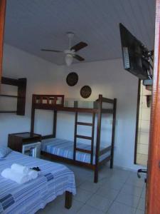 a bedroom with two bunk beds and a flat screen tv at Estalagem Sol de Boipeba in Ilha de Boipeba