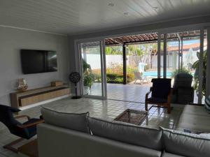 een woonkamer met een bank en stoelen en een televisie bij Casa di Barra in Barra de São Miguel