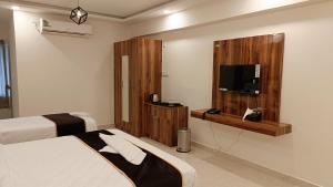 a hotel room with two beds and a flat screen tv at Hotel orchid inn in Bengaluru