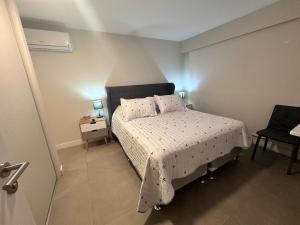 een kleine slaapkamer met een bed en een stoel bij Torre Green Life FullAmenities in Punta del Este