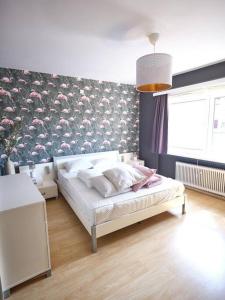 1 dormitorio con 1 cama y una pared con flores en Hugo by the harbor, light-filled and centrally located apartment - free parking, en Ostende